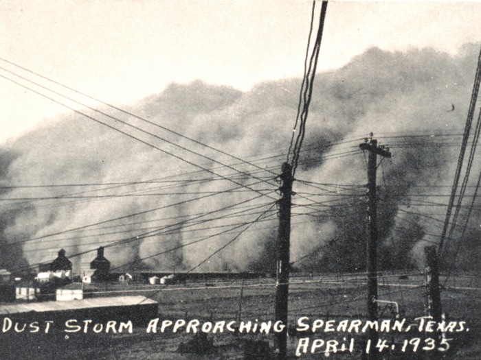 Schwarz-Weiß-Foto eines Staubsturms, der auf Spearman, Texas, zukommt, mit Strommasten im Vordergrund und dem Datum 14. April 1935 am unteren Rand.