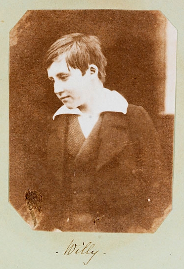 Porträt eines jungen Mannes in dunkler Kleidung auf einem sepiafarbenen Fotoalbum, unter dem der Name „Willy“ zu sehen ist.
