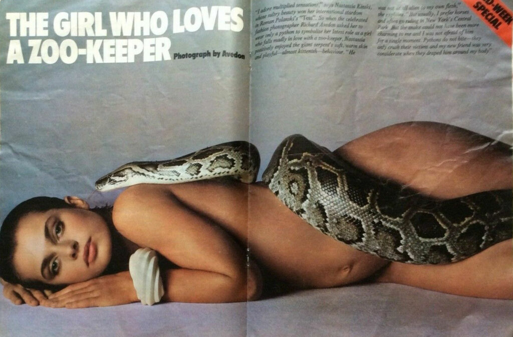 Eine Frau liegt mit zwei Schlangen, die über ihren Körper drapiert sind.